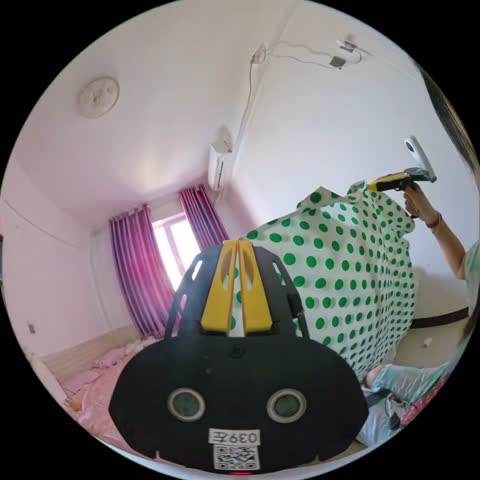 A pink bedroom with the curtains drawn, a polka-dot shirt held up in the gripper