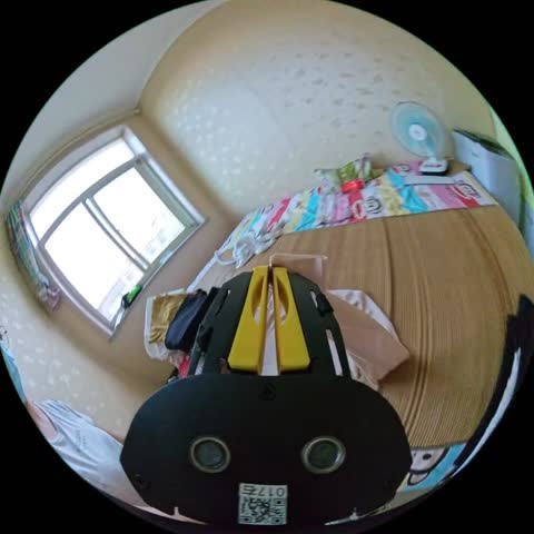 A small bedroom with a window, a desk fan and a patterned bedspread